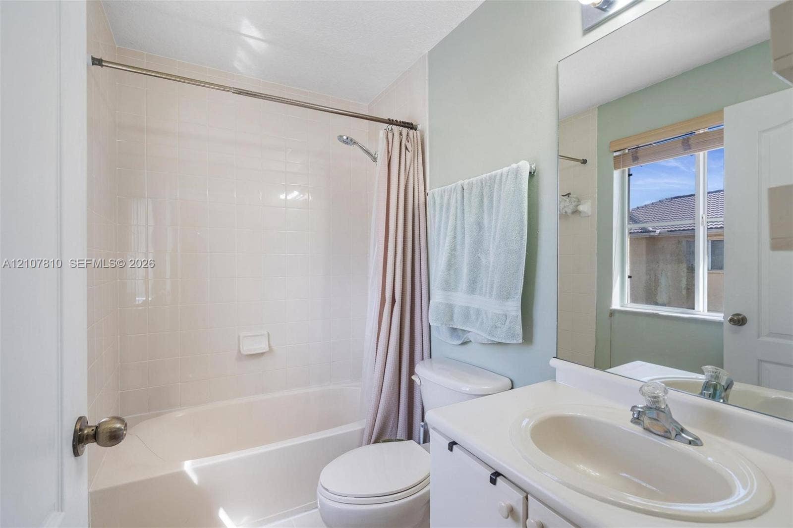 6940 NW 177th Street, #P105, Hialeah, Hialeah, FL 33015 Bathroom featuring a white vanity with an integrated sink, polished chrome faucet, full-width mirror, and a tub-shower combination with tiled surround