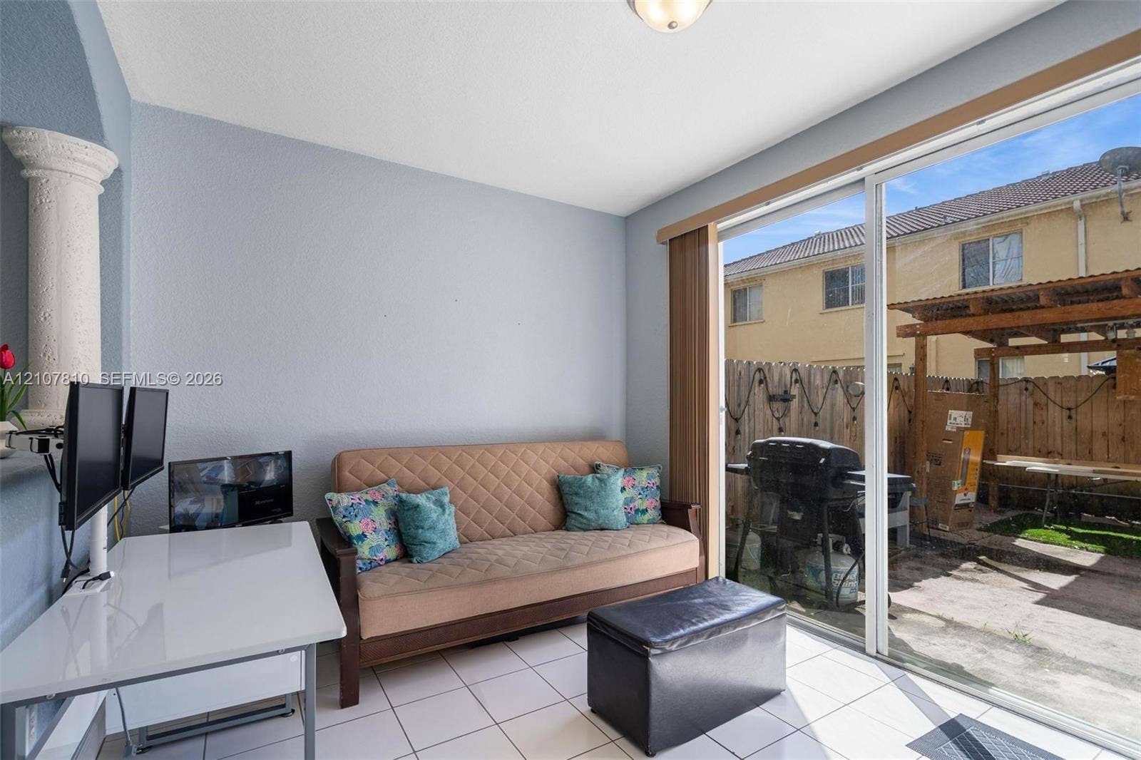 6940 NW 177th Street, #P105, Hialeah, Hialeah, FL 33015 Interior space featuring light-colored tile flooring, a decorative pillar, and a sliding glass door providing access to the exterior