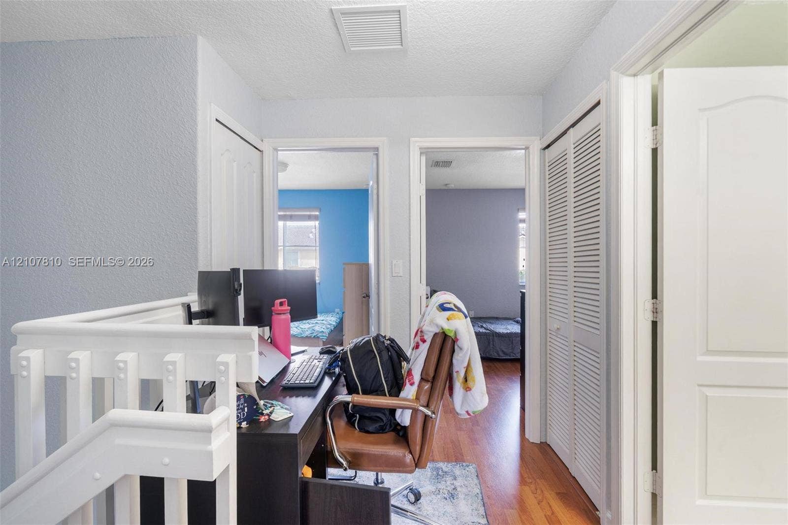 6940 NW 177th Street, #P105, Hialeah, Hialeah, FL 33015 Landing area featuring wood-finish flooring, a white wooden balustrade, and closet spaces with louvered bi-fold doors