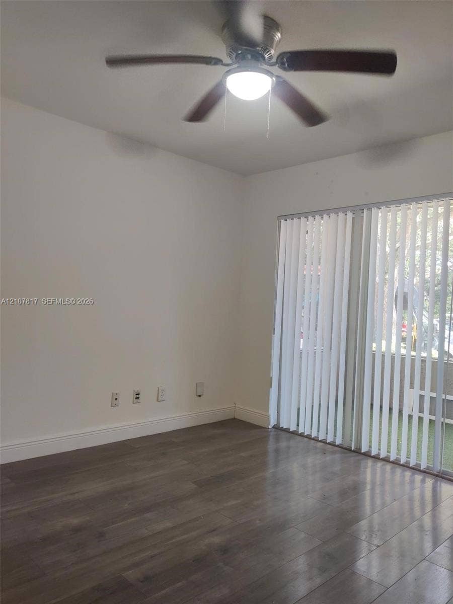 1705 Palm Cove Boulevard, #1-104, Delray Beach, Delray Beach, FL 33445 Room featuring wood-finish flooring, a ceiling fan with integrated lighting, and a large sliding glass door with vertical blinds