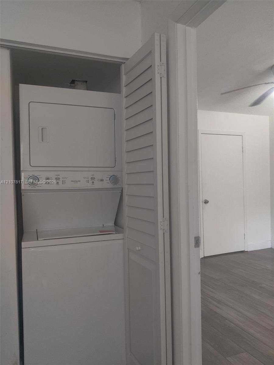 1705 Palm Cove Boulevard, #1-104, Delray Beach, Delray Beach, FL 33445 Laundry closet featuring a white stacked washer and dryer unit enclosed by louvered bi-fold doors