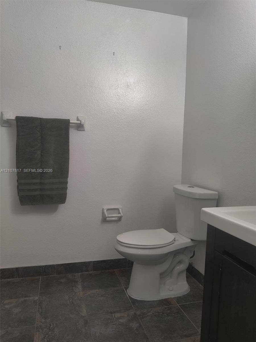 1705 Palm Cove Boulevard, #1-104, Delray Beach, Delray Beach, FL 33445 Dark-toned vanity with a rectangular sink, white commode, and dark tile flooring