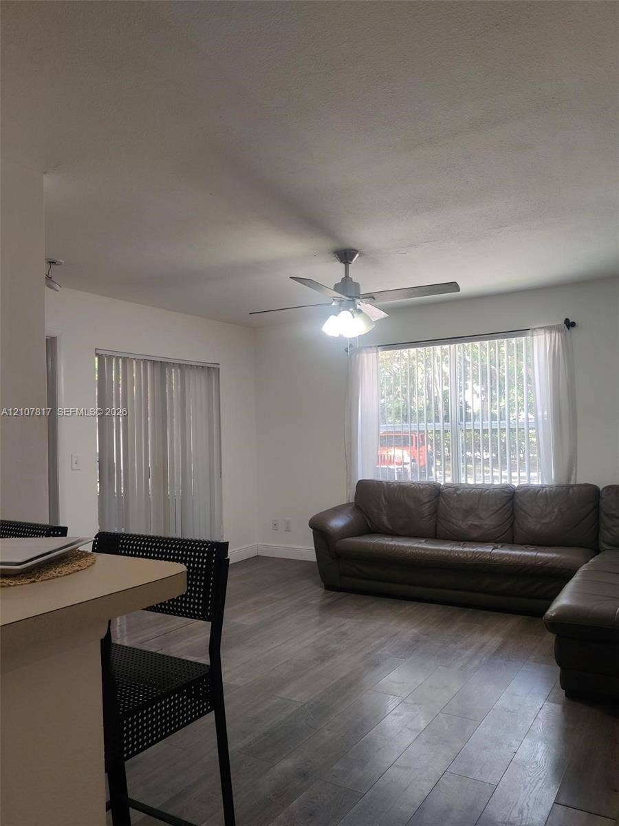 1705 Palm Cove Boulevard, #1-104, Delray Beach, Delray Beach, FL 33445 Interior space featuring wood-finish flooring, a ceiling fan with integrated lighting, and sliding glass doors