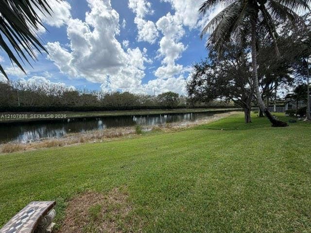 133 Cameron Drive, Weston, FL 33326 Waterfront grounds featuring a manicured lawn, mature palm trees, and canal frontage
