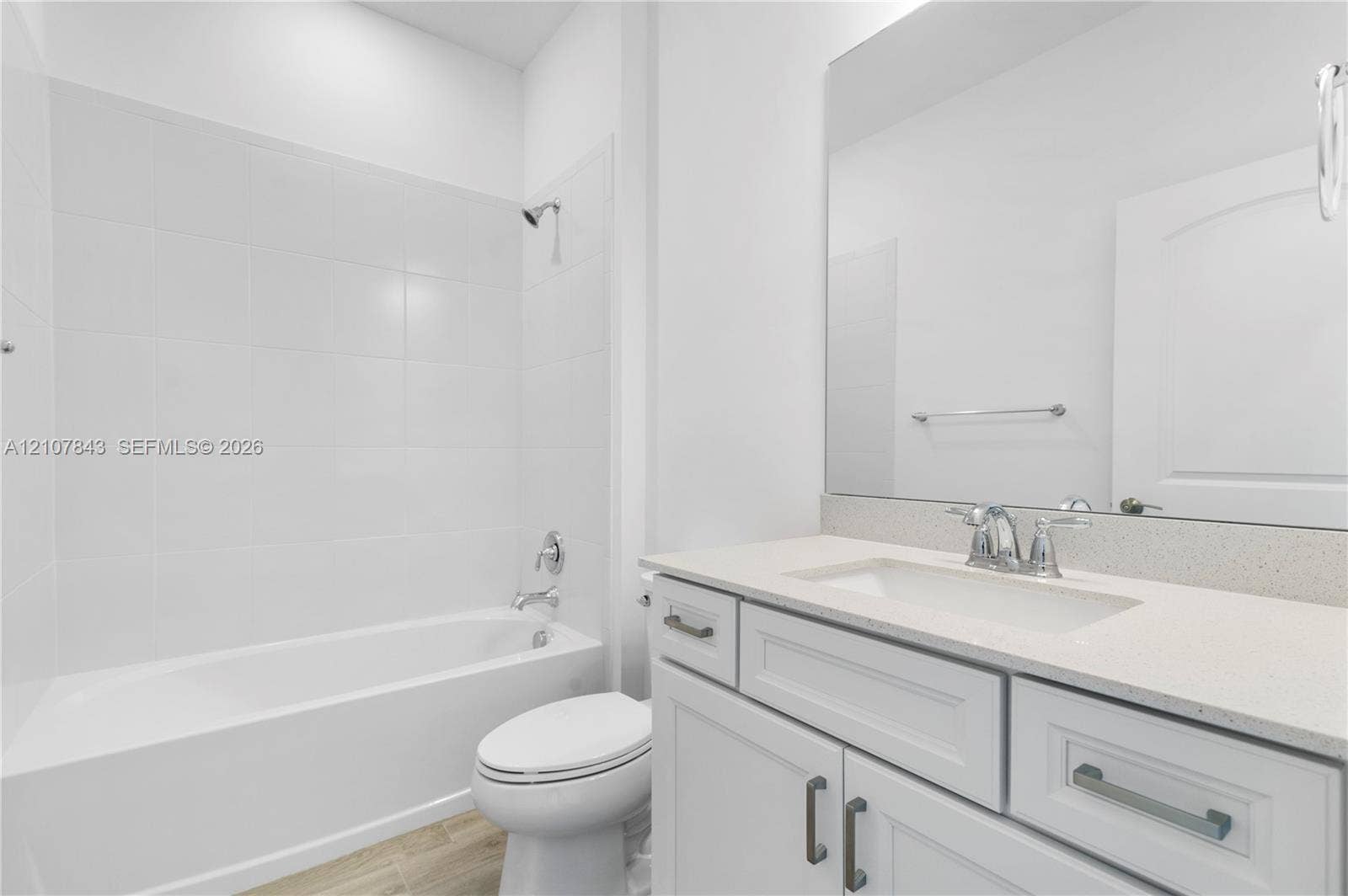 4949 Blistering Way, Lake Worth, FL 33467 Bathroom featuring a vanity with a light-toned solid surface countertop, white shaker-style cabinetry, a large wall-mounted mirror, and a tub-shower combination with floor-to-ceiling tile surround