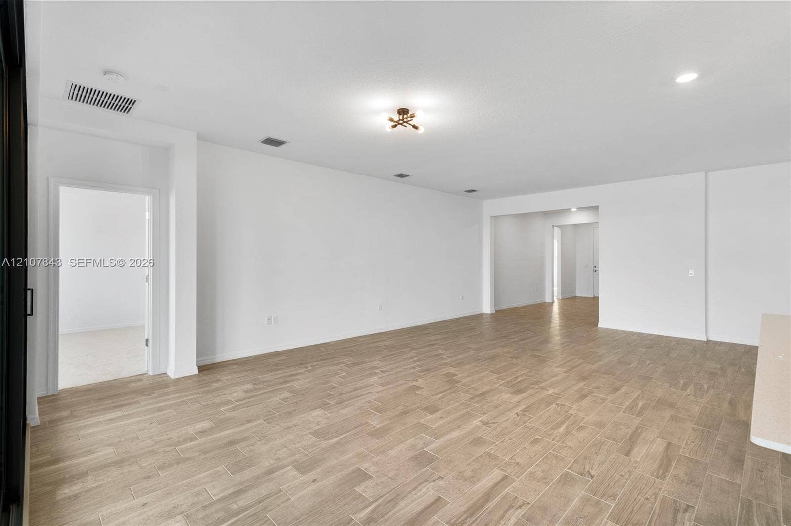 4949 Blistering Way, Lake Worth, FL 33467 Open interior space featuring wood-finish flooring, recessed lighting, and a multi-arm metallic light fixture