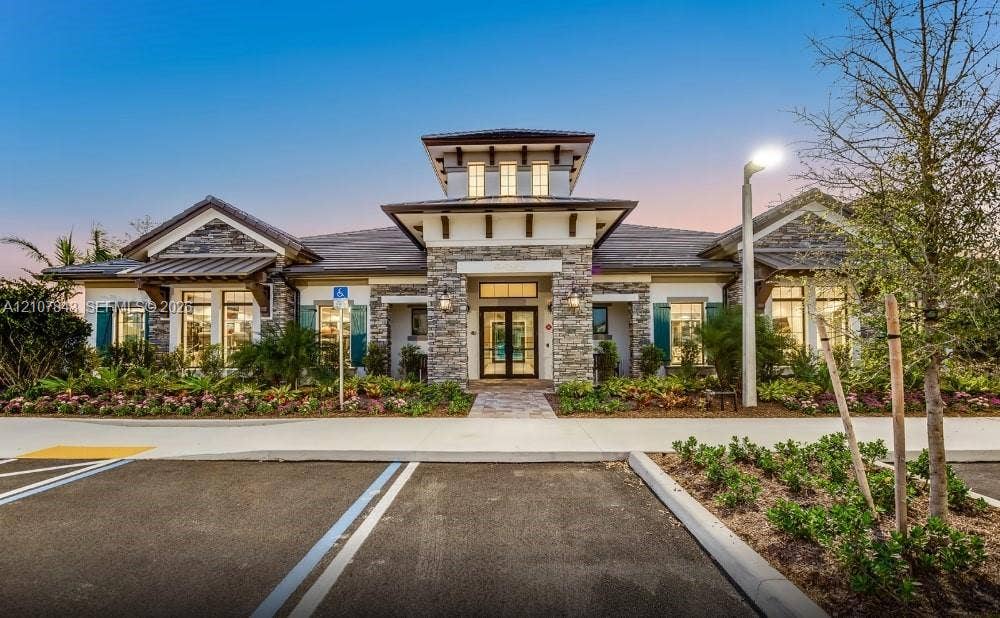 4949 Blistering Way, Lake Worth, FL 33467 Exterior faade featuring natural stone veneer, a multi-tiered roofline with a central cupola, decorative shutters, metal accent roofing, and professional landscaping