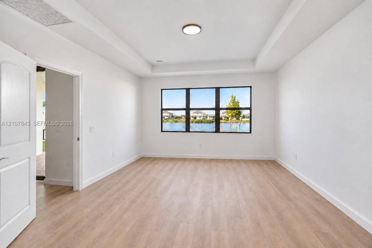 4949 Blistering Way, Lake Worth, FL 33467 Room featuring wood-finish flooring, a tray ceiling, flush-mount lighting, and expansive windows with water scenery