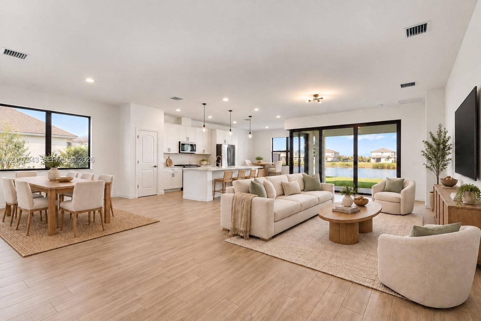 4949 Blistering Way, Lake Worth, FL 33467 Open-concept main living area featuring wood-finish flooring, a kitchen island with stone-style countertops, recessed lighting, and large sliding glass doors providing outdoor exposure