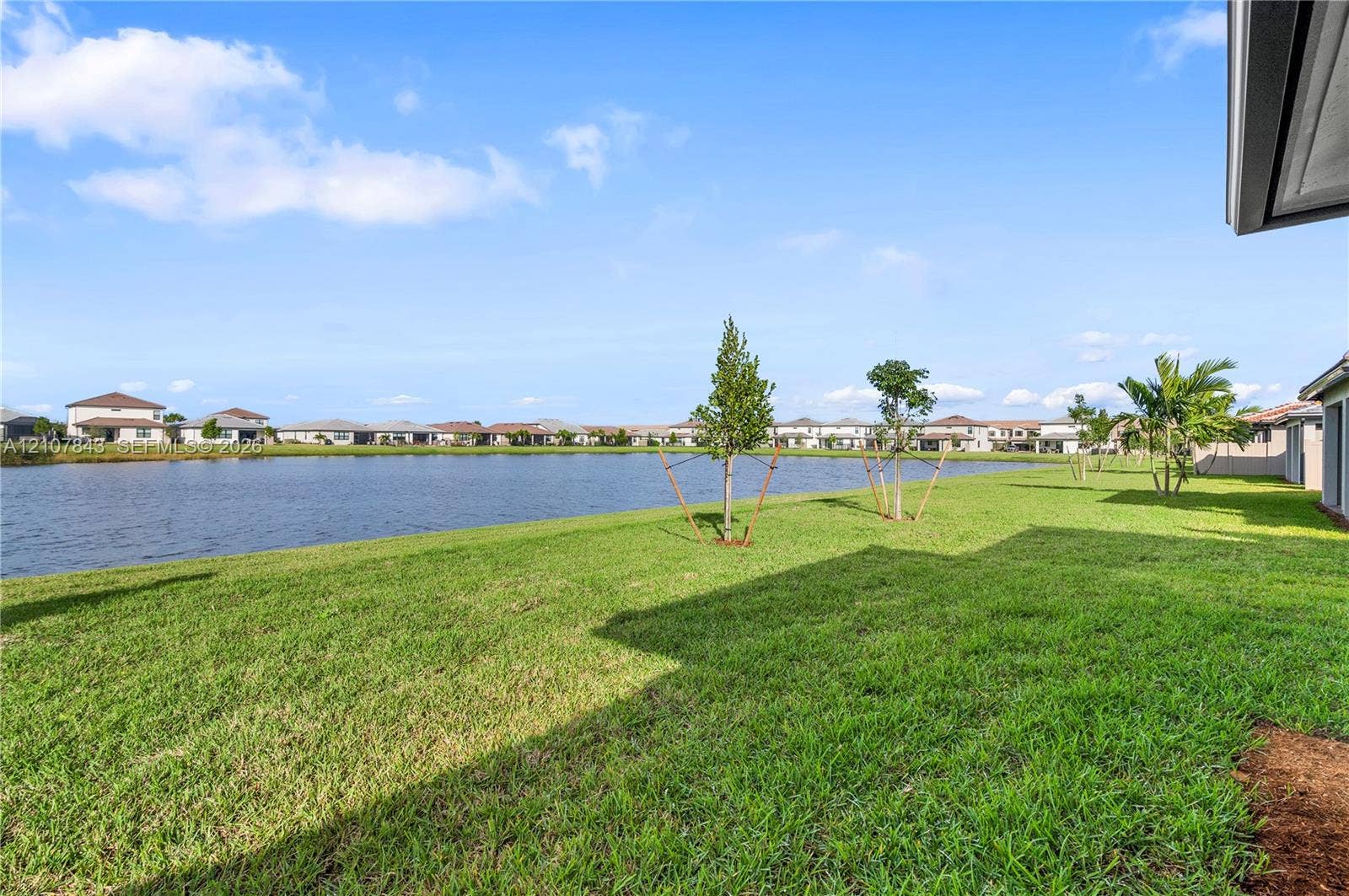 4949 Blistering Way, Lake Worth, FL 33467 Expansive backyard featuring a grass lawn, waterfront positioning, and young trees