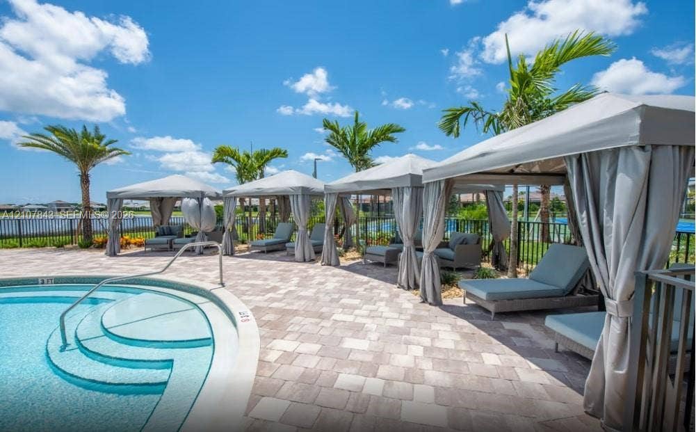4949 Blistering Way, Lake Worth, FL 33467 Outdoor swimming pool with integrated steps, surrounded by a stone paver deck and multiple covered cabanas
