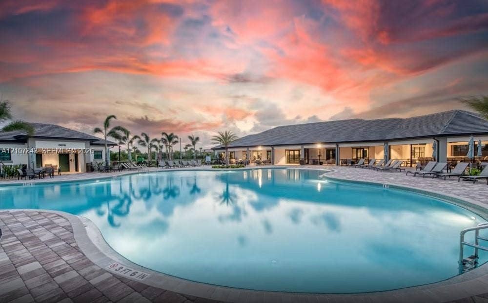 4949 Blistering Way, Lake Worth, FL 33467 Resort-style swimming pool featuring a paver deck, perimeter palm trees, and structural tile roof buildings