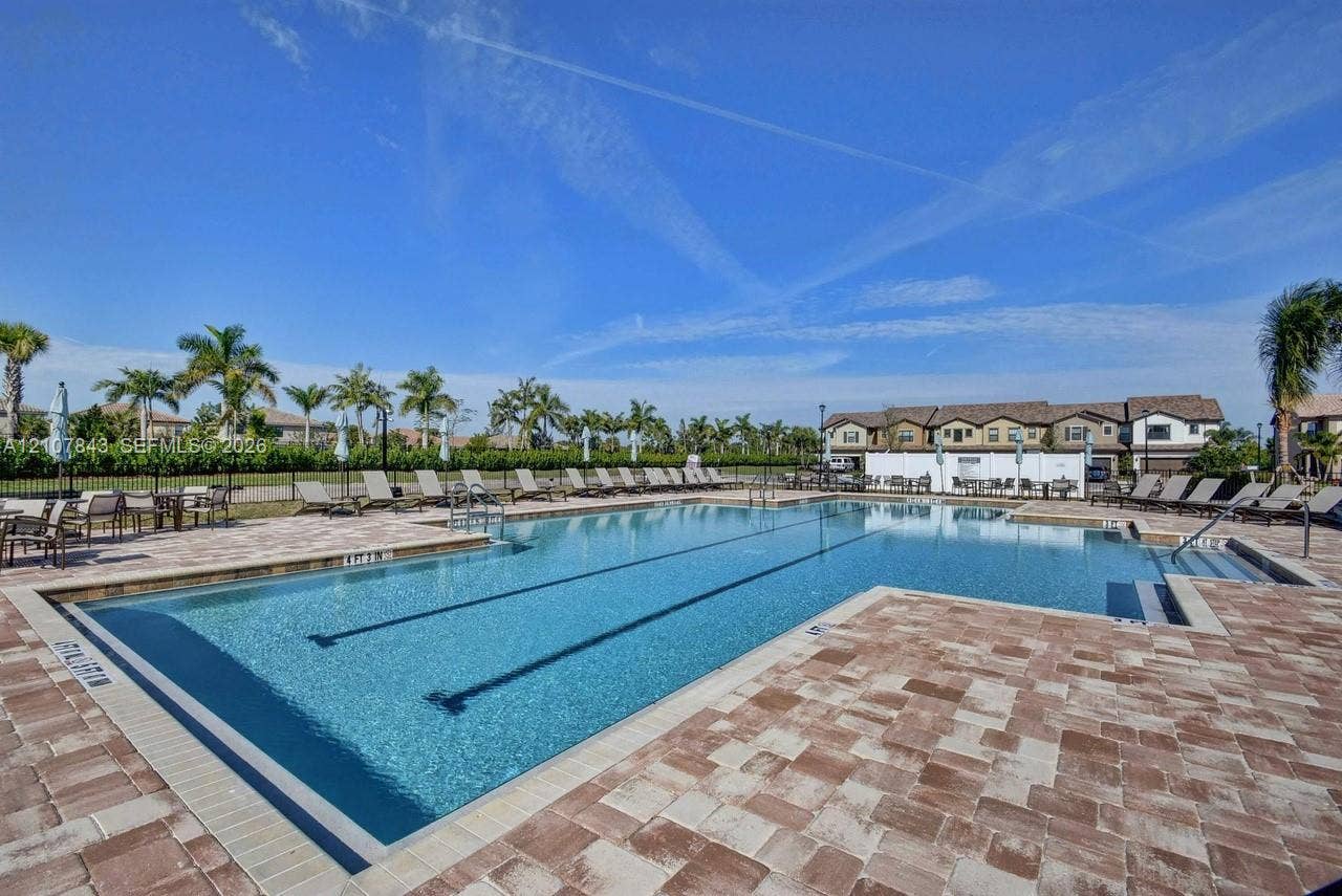 4949 Blistering Way, Lake Worth, FL 33467 Community swimming pool featuring a paved deck, perimeter fencing, designated lap lanes, and mature palm trees