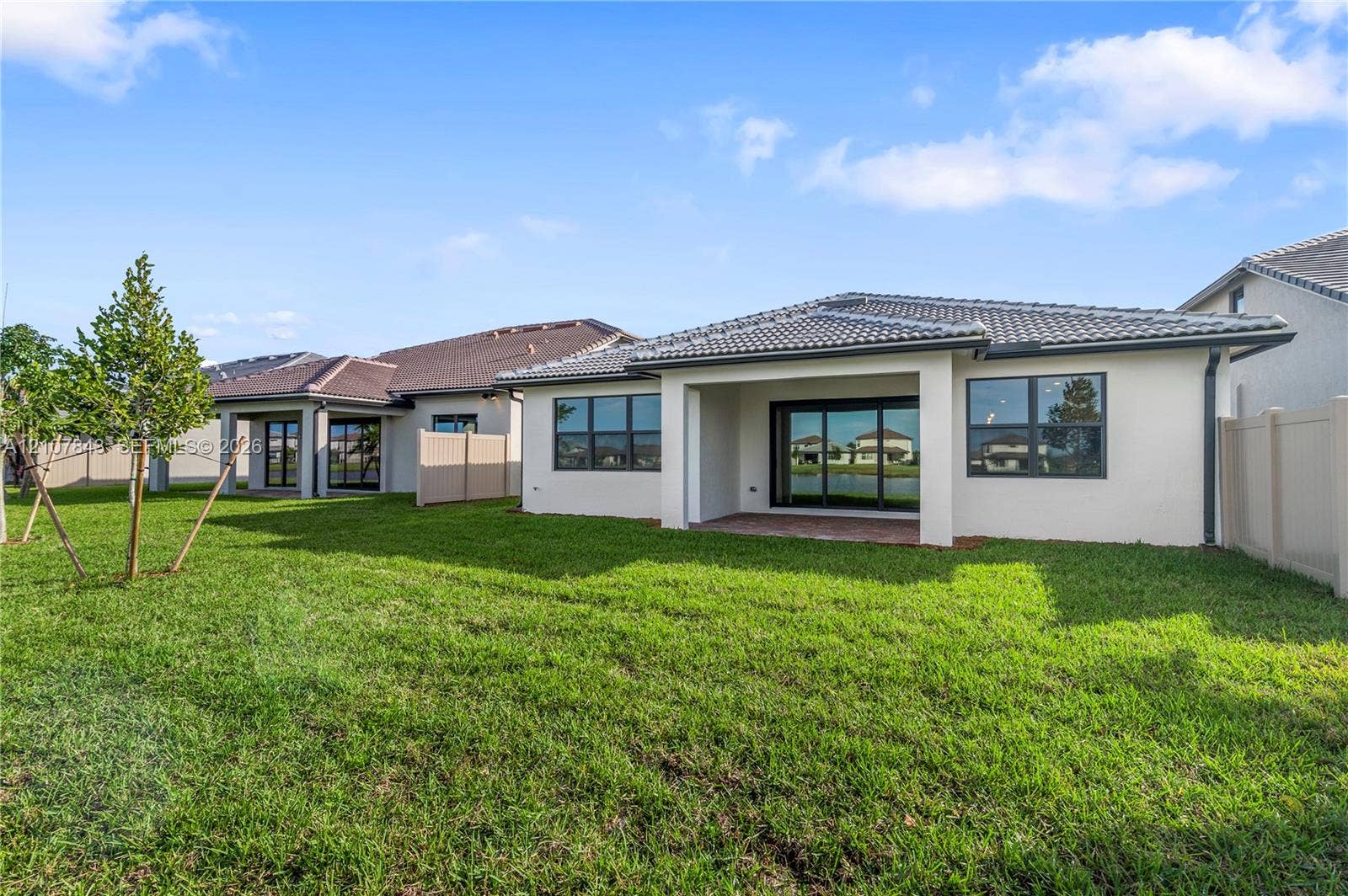 4949 Blistering Way, Lake Worth, FL 33467 Stucco exterior featuring a covered patio, tile roof, large sliding glass doors, and vinyl privacy fencing