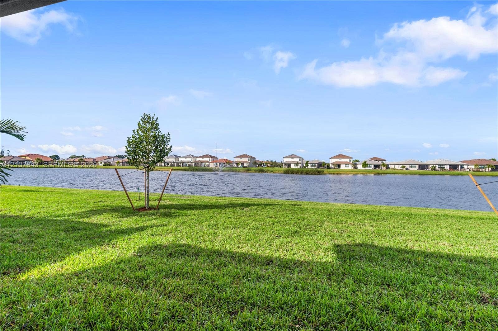 4949 Blistering Way, Lake Worth, FL 33467 Waterfront backyard featuring a manicured lawn and a central water feature