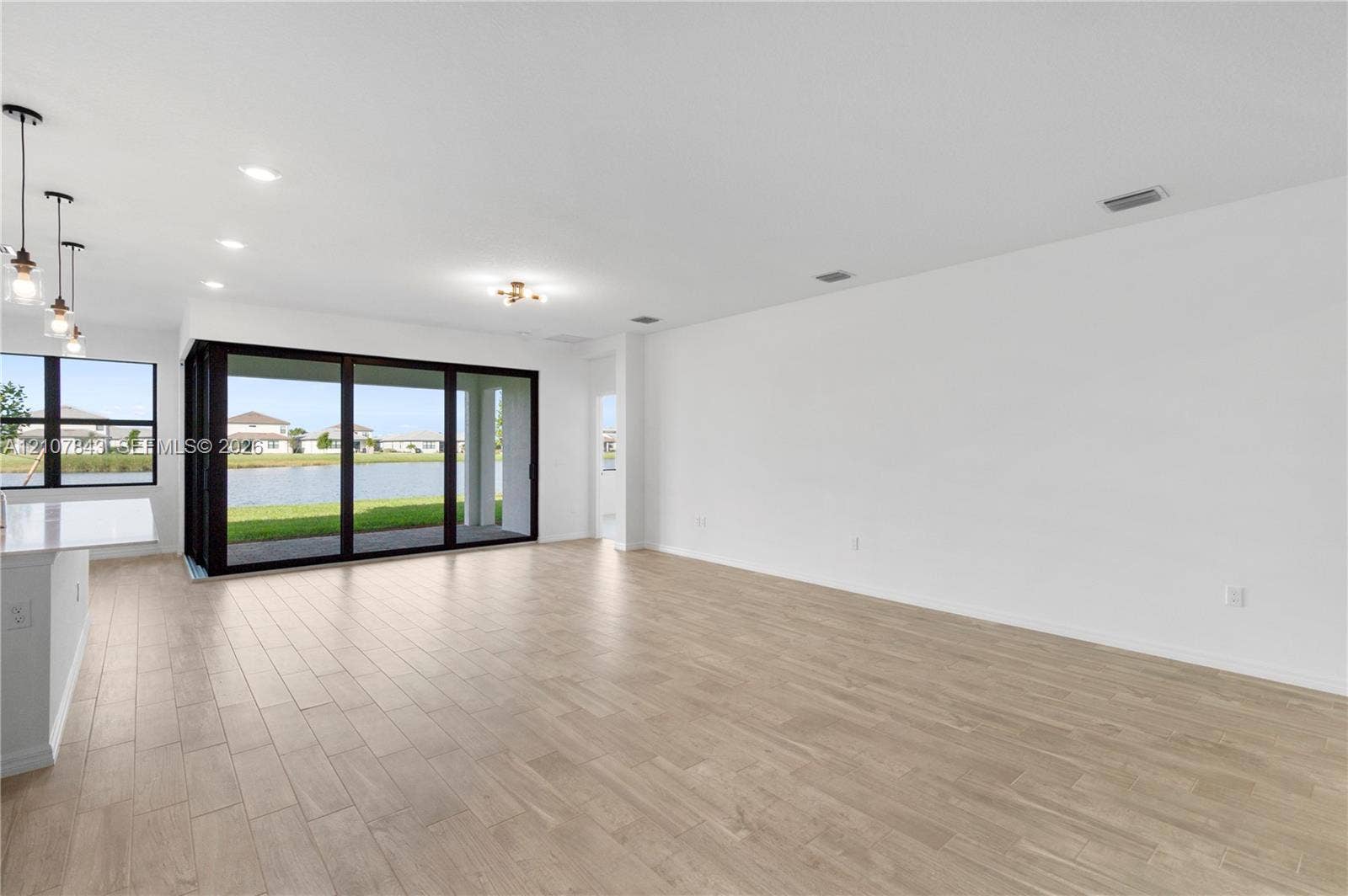 4949 Blistering Way, Lake Worth, FL 33467 Open-concept interior featuring wood-finish flooring, multi-panel sliding glass doors, and pendant lighting