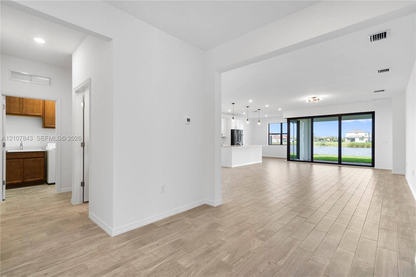 4949 Blistering Way, Lake Worth, FL 33467 Wood-finish tile flooring, recessed lighting, expansive glass sliding doors, and water scenery