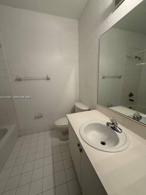 Bathroom featuring a vanity with integrated sink, chrome-finish faucet, large wall-mounted mirror, ceramic tile flooring, and a shower-tub combination
