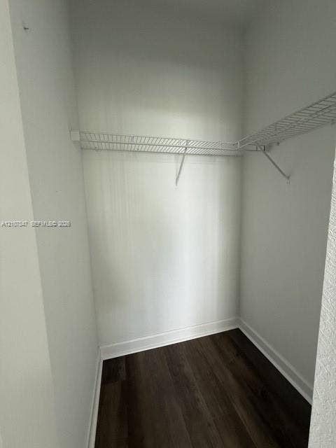 Walk-in closet featuring white wire shelving and dark wood-finish flooring