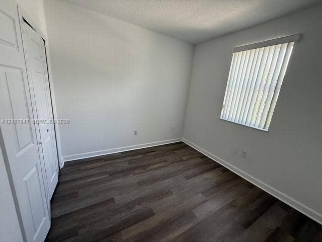 Neutral wall coloring, wood-finish flooring, and built-in closet with panel doors, featuring a window with vertical blinds