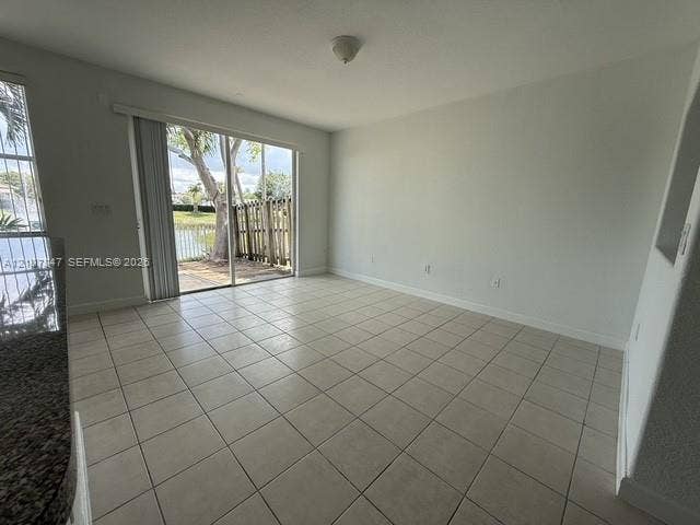 Ceramic tile flooring, sliding glass door with exterior access, stone-finish countertop, and built-in wall niche