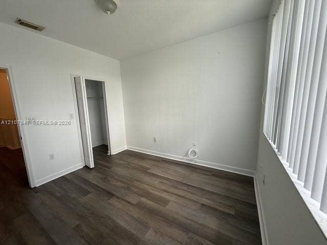 Interior space featuring wood-finish flooring, white walls, vertical blinds, and a bi-fold door closet