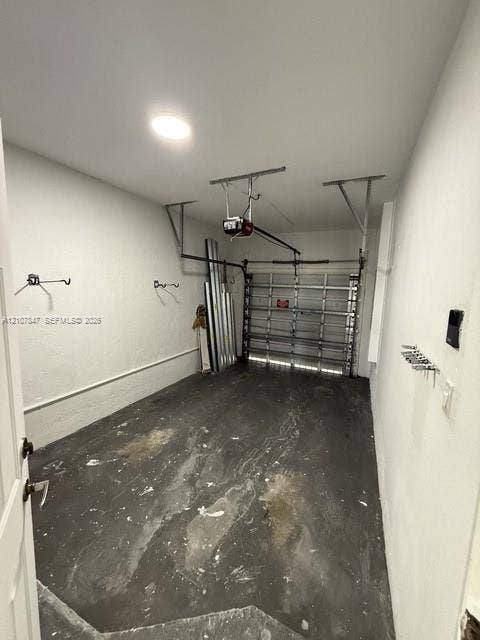 Enclosed garage featuring an automated overhead door system, ceiling-mounted lighting, and wall-mounted storage hardware