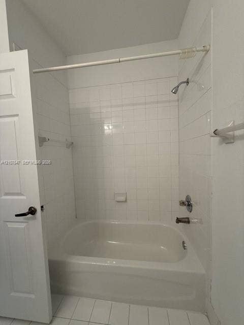 Bathtub and shower combination featuring a white tile surround, integrated soap dish, polished chrome fixtures, and a six-panel door