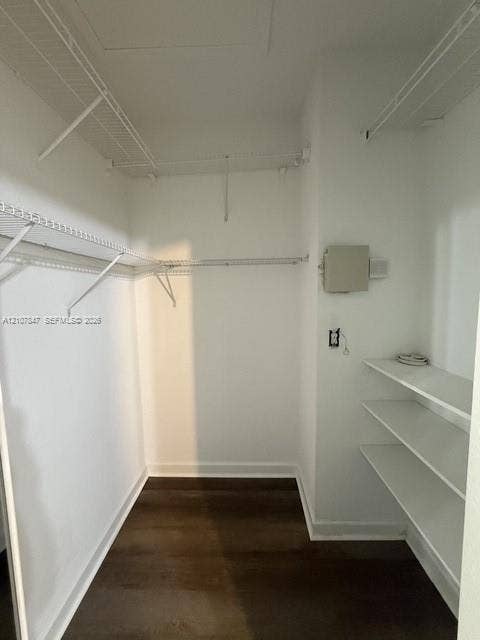 Storage space featuring white wire shelving, tiered built-in shelving, and wood-finish flooring