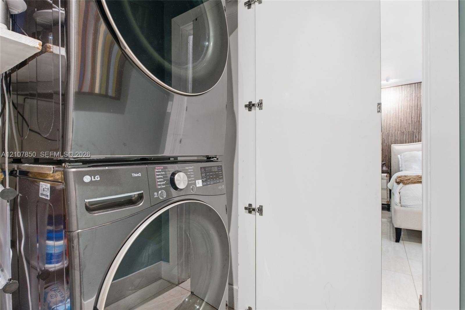 Stacked stainless steel laundry appliances housed within a white cabinetry enclosure