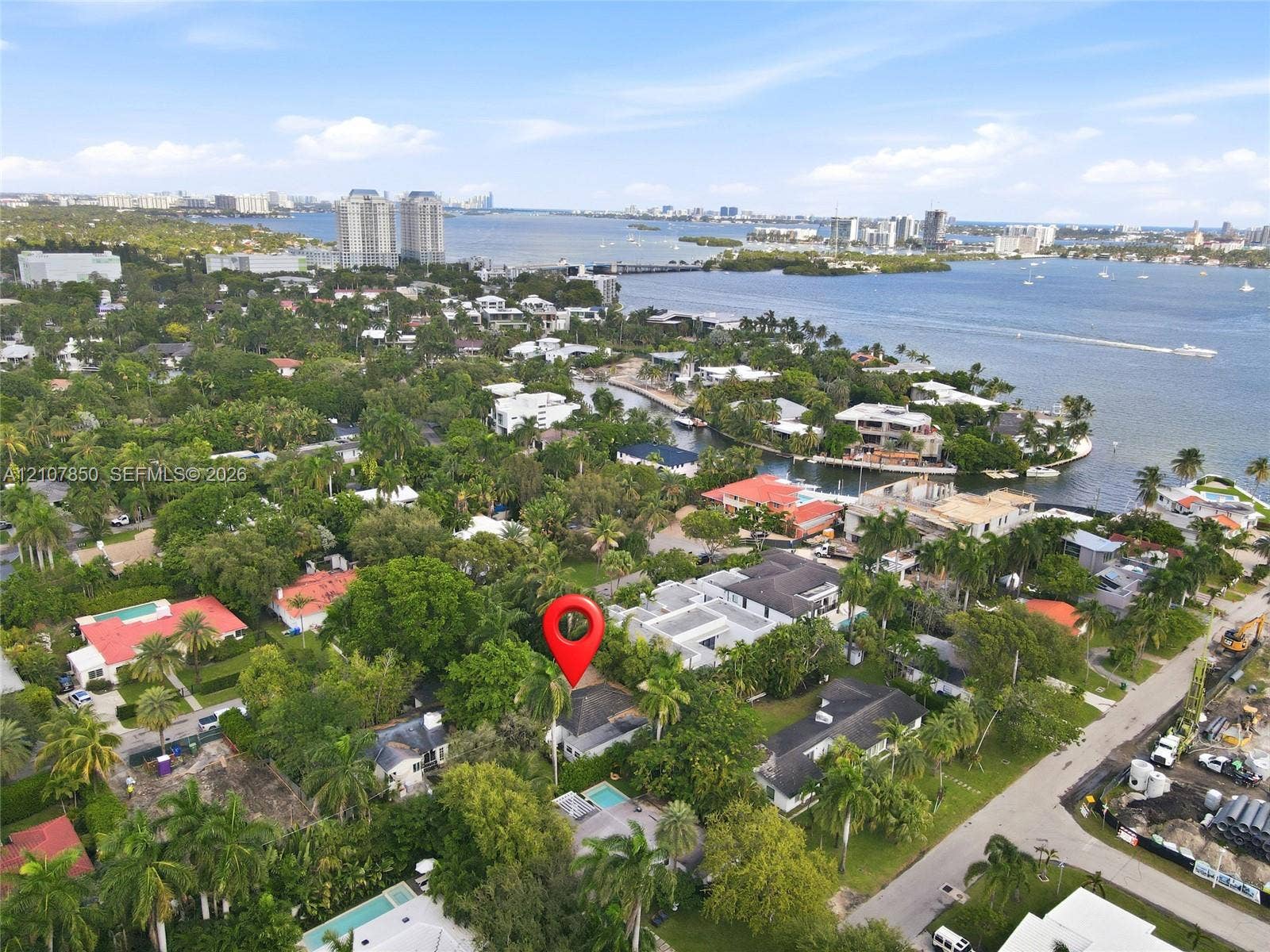 Aerial perspective of a residential property featuring mature landscaping, a swimming pool, and established trees within a coastal neighborhood