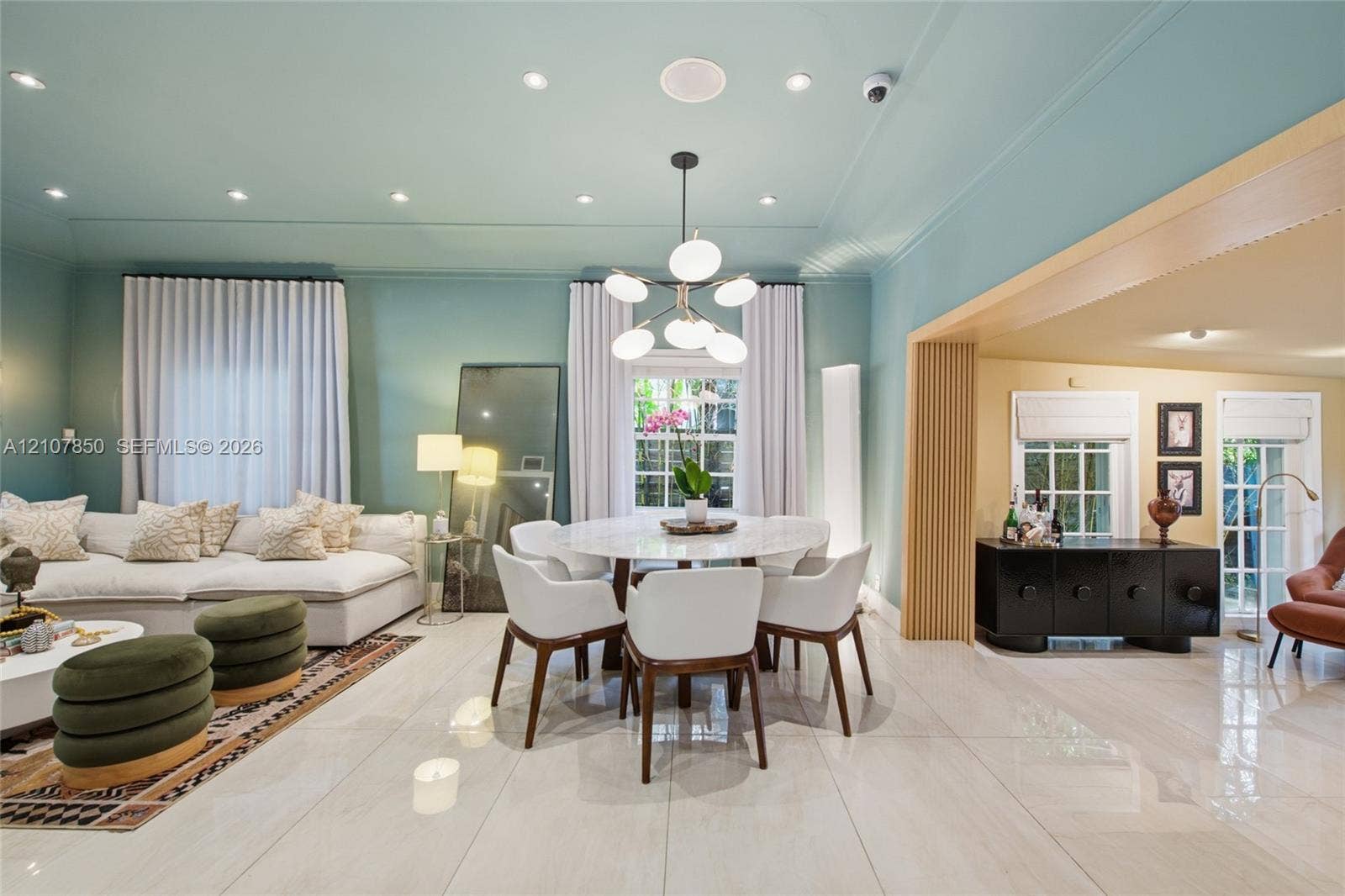 Large-format polished tile flooring, multi-globe chandelier with matte black finish, recessed ceiling lighting, and fluted wood column accents
