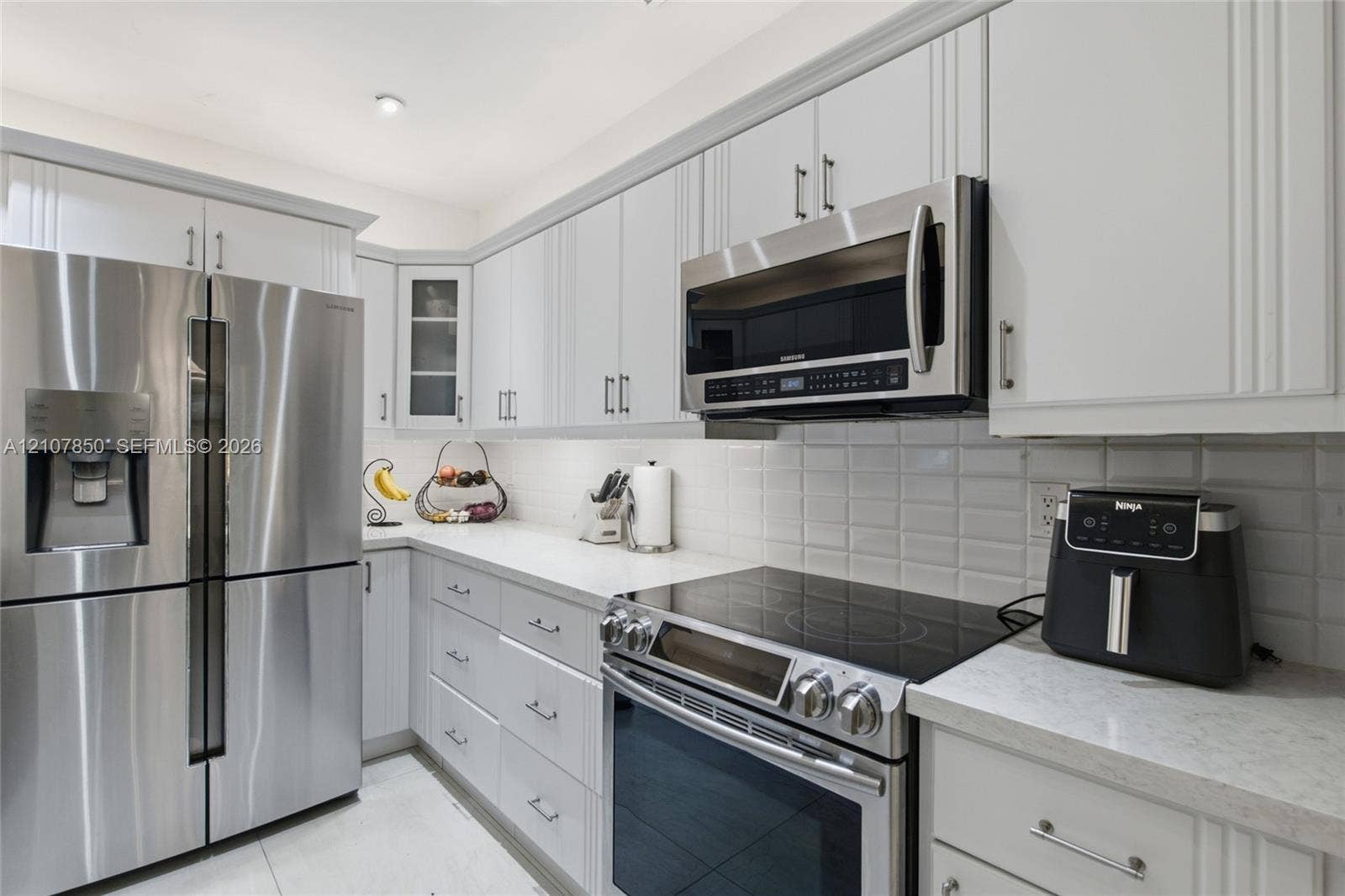 Kitchen featuring white shaker-style cabinetry, stainless steel appliances, white quartz countertops, and a subway tile backsplash