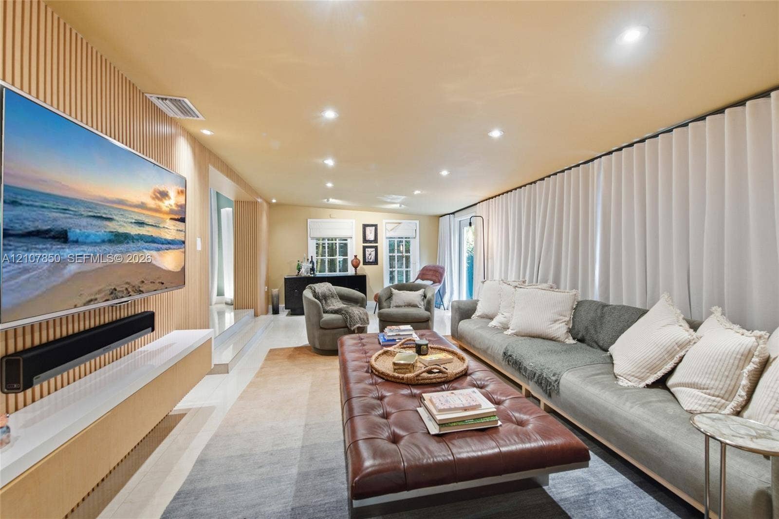 Accent wall featuring vertical wood slat detailing, floating wall-mounted media console, recessed ceiling lighting, and wall-to-wall drapery