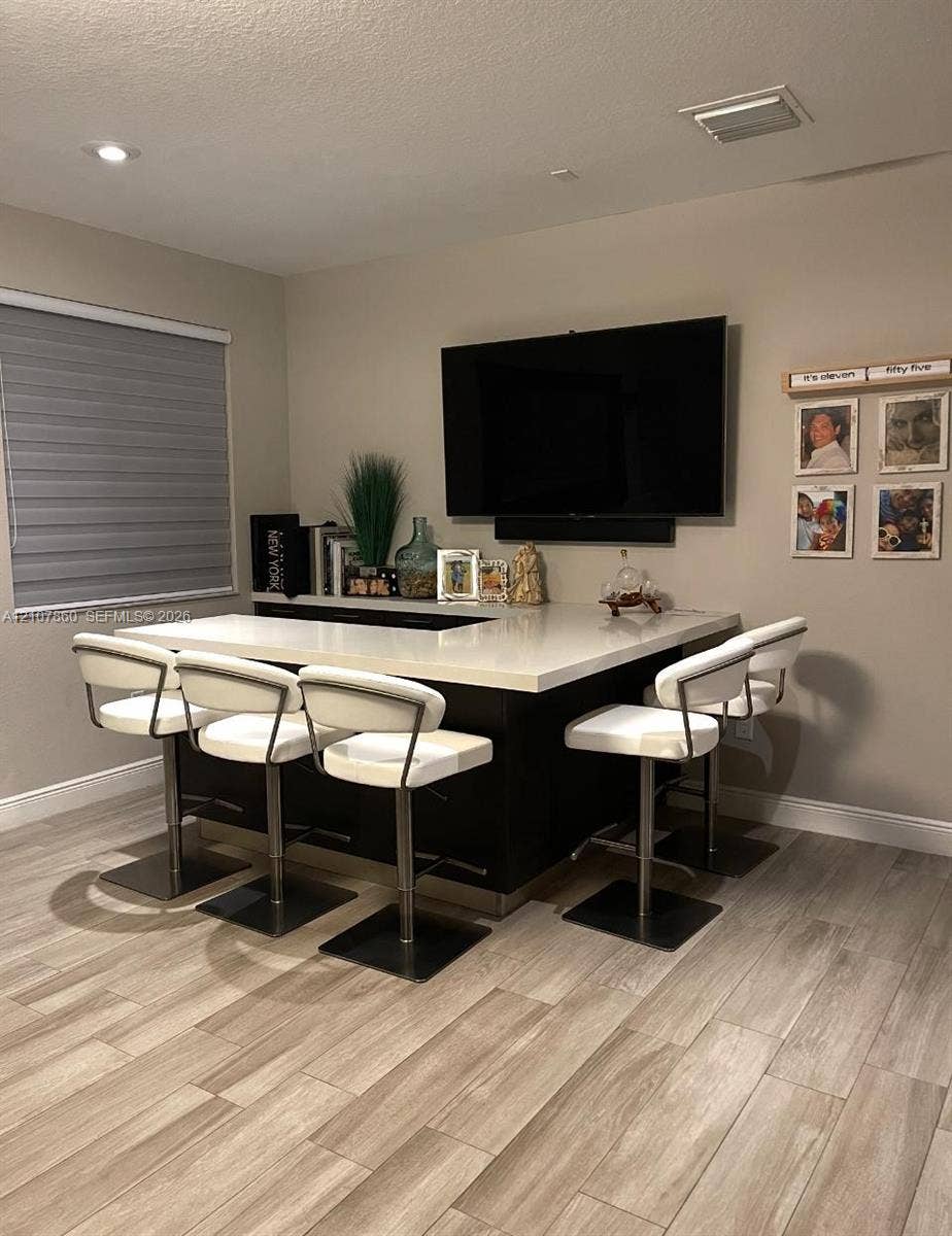 8925 NW 99th Court, Doral, FL 33178 Custom built-in wet bar featuring dark cabinetry, a solid surface countertop, wood-finish flooring, and recessed ceiling lighting