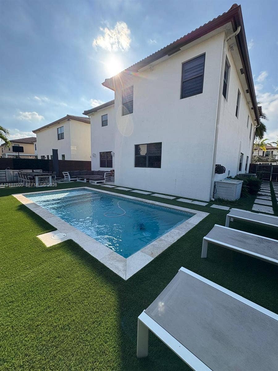 8925 NW 99th Court, Doral, FL 33178 Rectangular swimming pool featuring stone coping, synthetic turf landscaping, and paved hardscaping