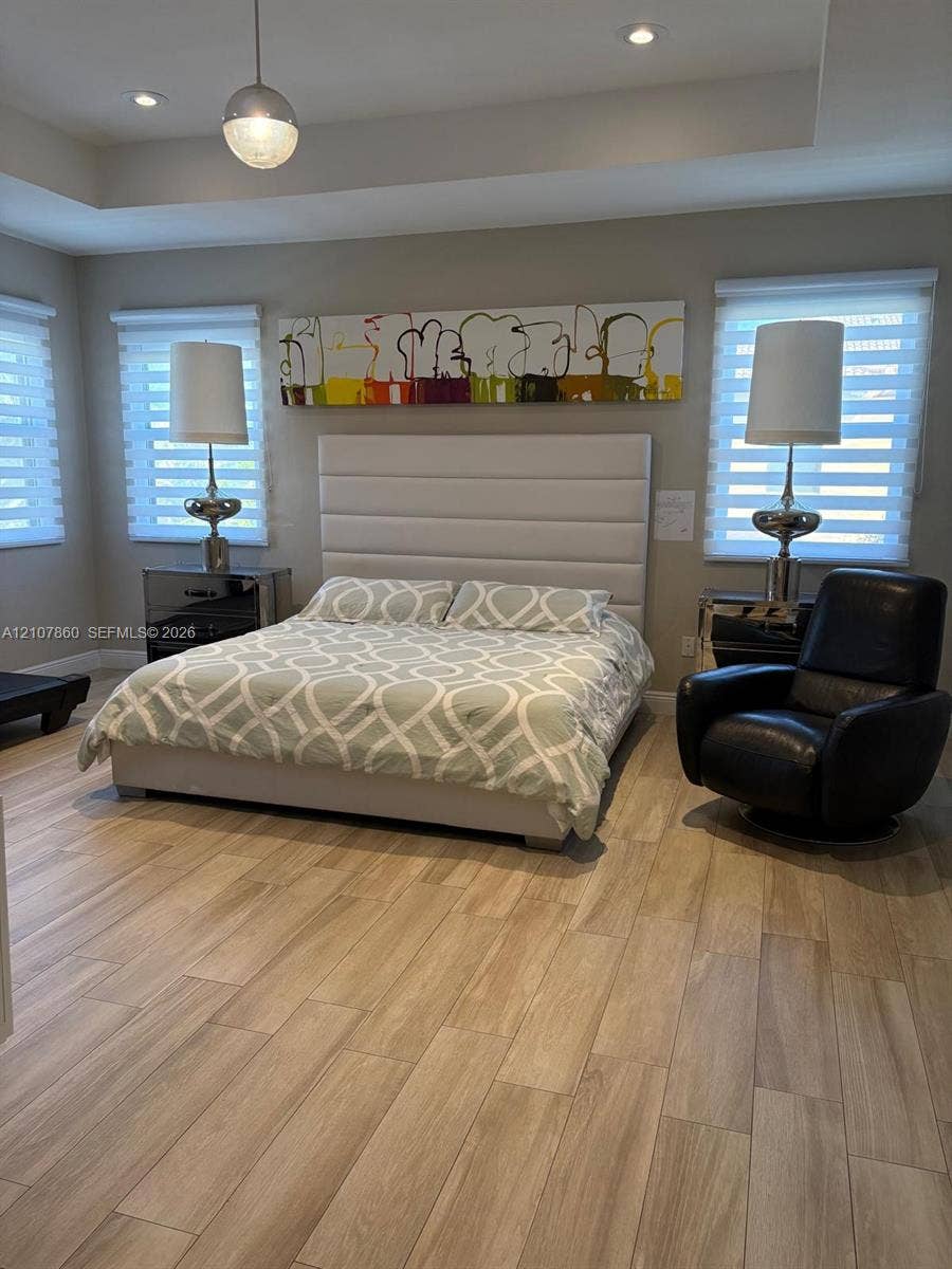 8925 NW 99th Court, Doral, FL 33178 Tray ceiling featuring recessed lighting, wood-finish flooring, and dual windows with motorized roller shades