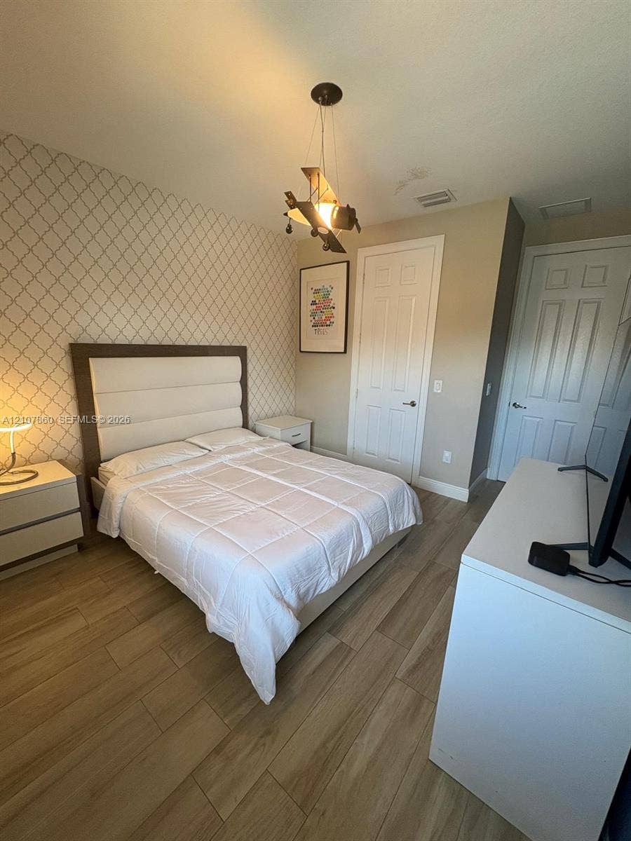 8925 NW 99th Court, Doral, FL 33178 Wood-finish flooring, patterned accent wall, and multi-panel interior doors