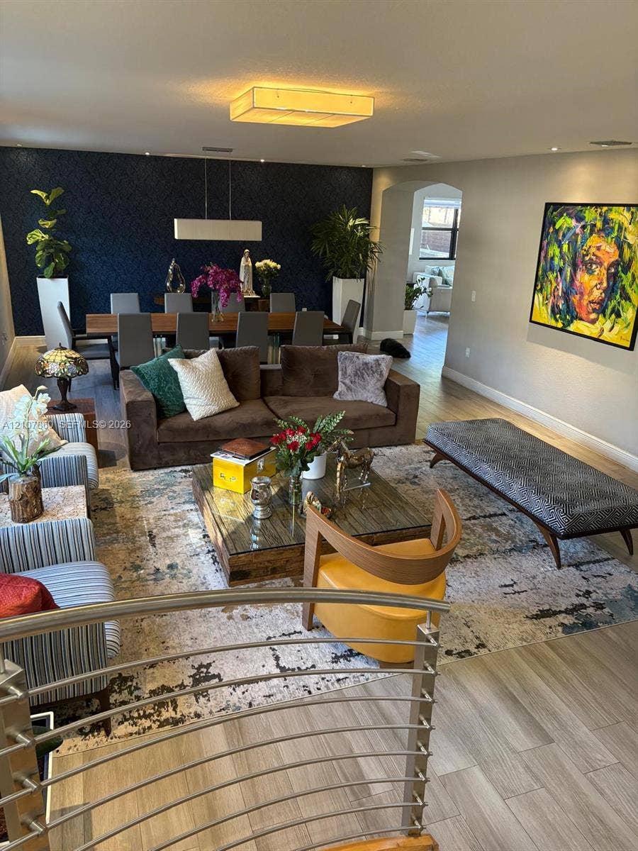 8925 NW 99th Court, Doral, FL 33178 Open-concept space featuring wood-finish flooring, a textured dark navy accent wall, recessed lighting, and a stainless steel cable railing system