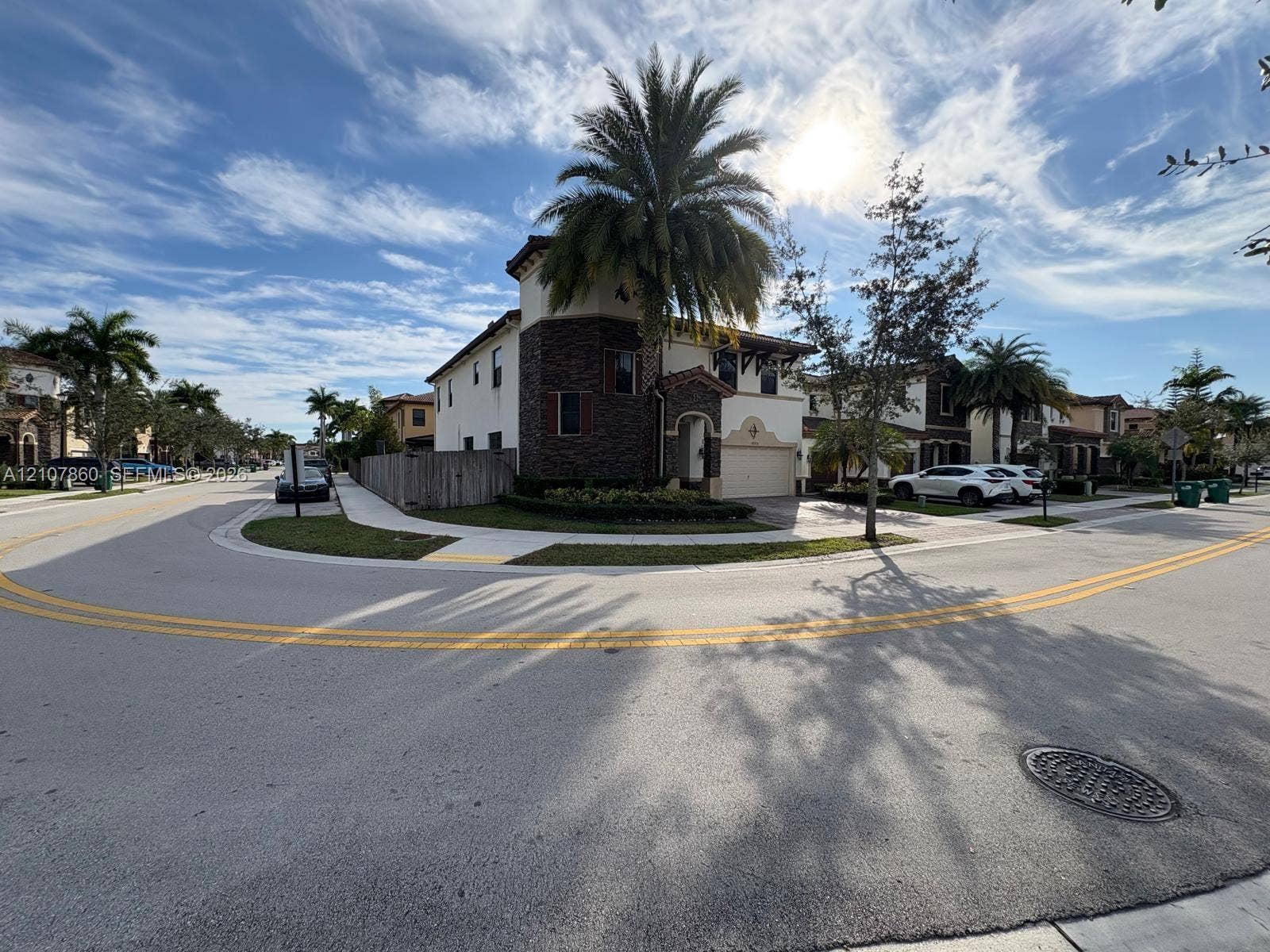 8925 NW 99th Court, Doral, FL 33178 Corner lot residence featuring a two-story exterior, stacked stone facade accents, arched entryway, and attached garage