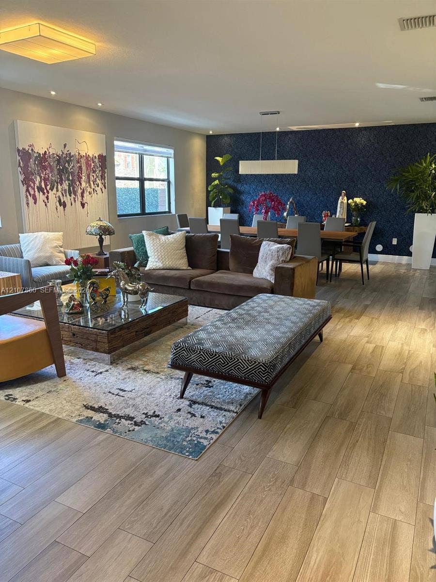 8925 NW 99th Court, Doral, FL 33178 Wood-finish flooring throughout, navy blue accent wall, recessed lighting, and rectangular pendant light fixture