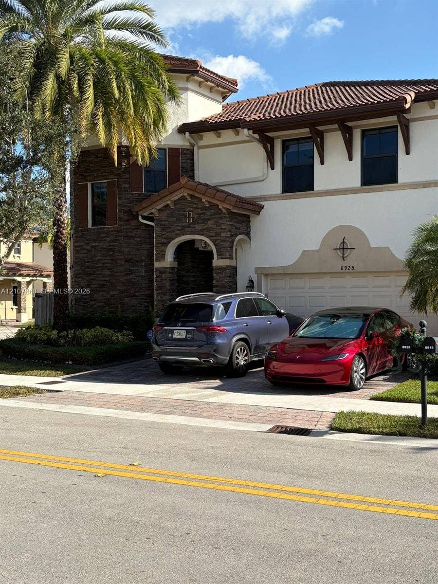8925 NW 99th Court, Doral, FL 33178 Stucco exterior featuring decorative stone veneer masonry, tiled roof with exposed rafter tails, and paver driveway