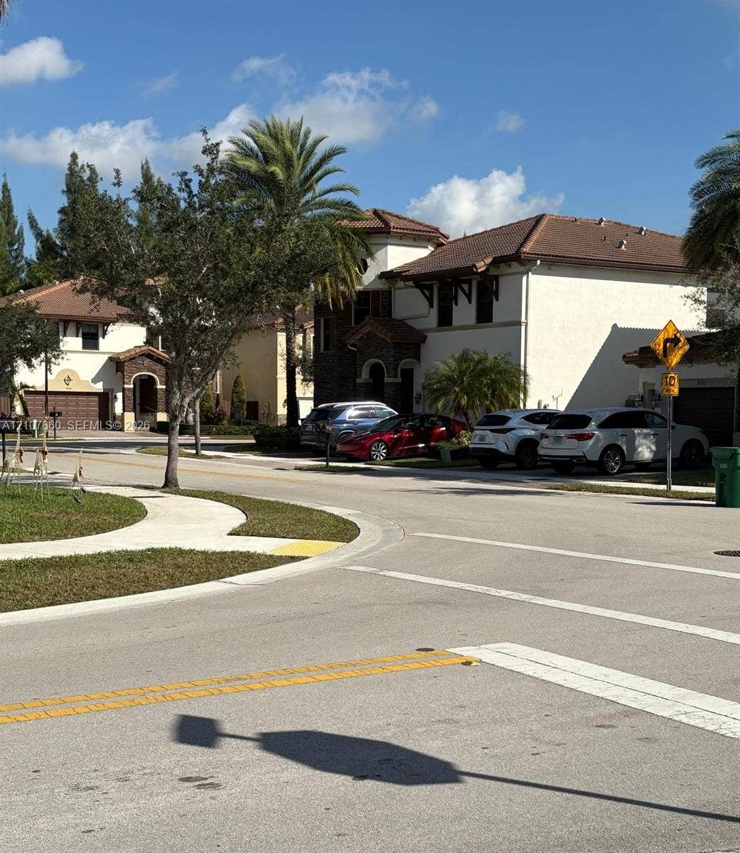 8925 NW 99th Court, Doral, FL 33178 Two-story exterior featuring a light-colored stucco facade, decorative stone masonry accents, a tiled roof, and arched entryway elements