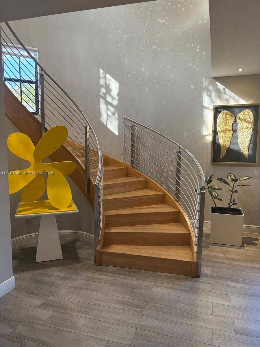 8925 NW 99th Court, Doral, FL 33178 Curved staircase featuring wood treads and a stainless steel cable railing system