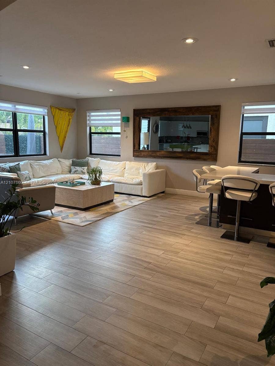 8925 NW 99th Court, Doral, FL 33178 Open-concept interior featuring wood-finish tile flooring, recessed lighting, and a large wall-mounted mirror with a wood frame