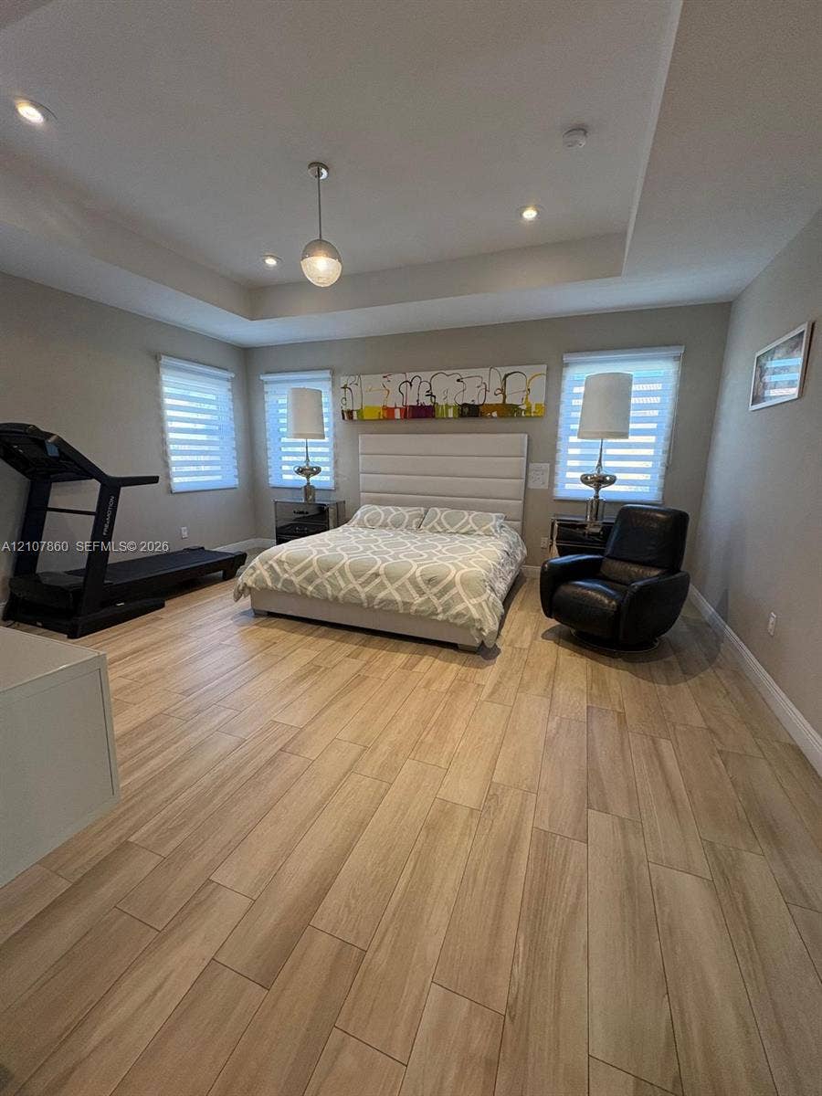 8925 NW 99th Court, Doral, FL 33178 Spacious room featuring wood-finish flooring, recessed lighting, a tray ceiling, and windows fitted with roller shades