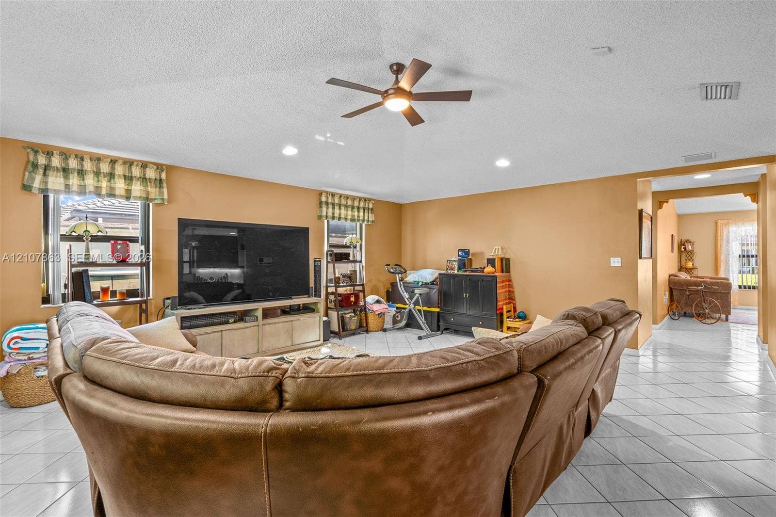 Open-concept interior featuring light-colored tile flooring, neutral wall paint, recessed lighting, and a ceiling fan