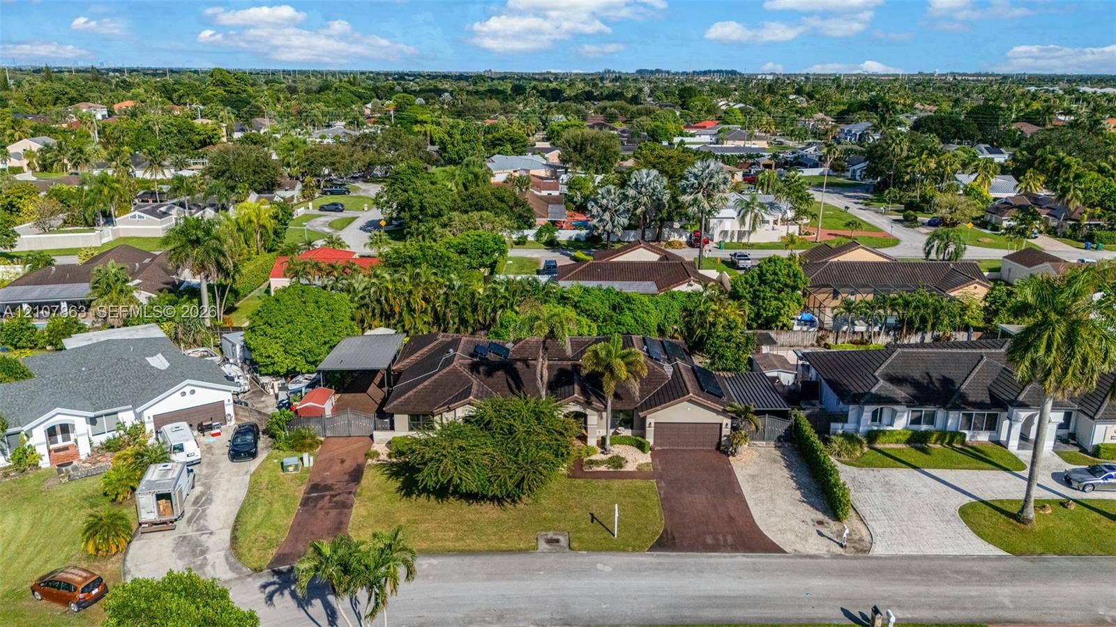 Aerial perspective of a single-story residence featuring a multi-pitched roof, dual paved driveways, an attached garage, and mature landscaping