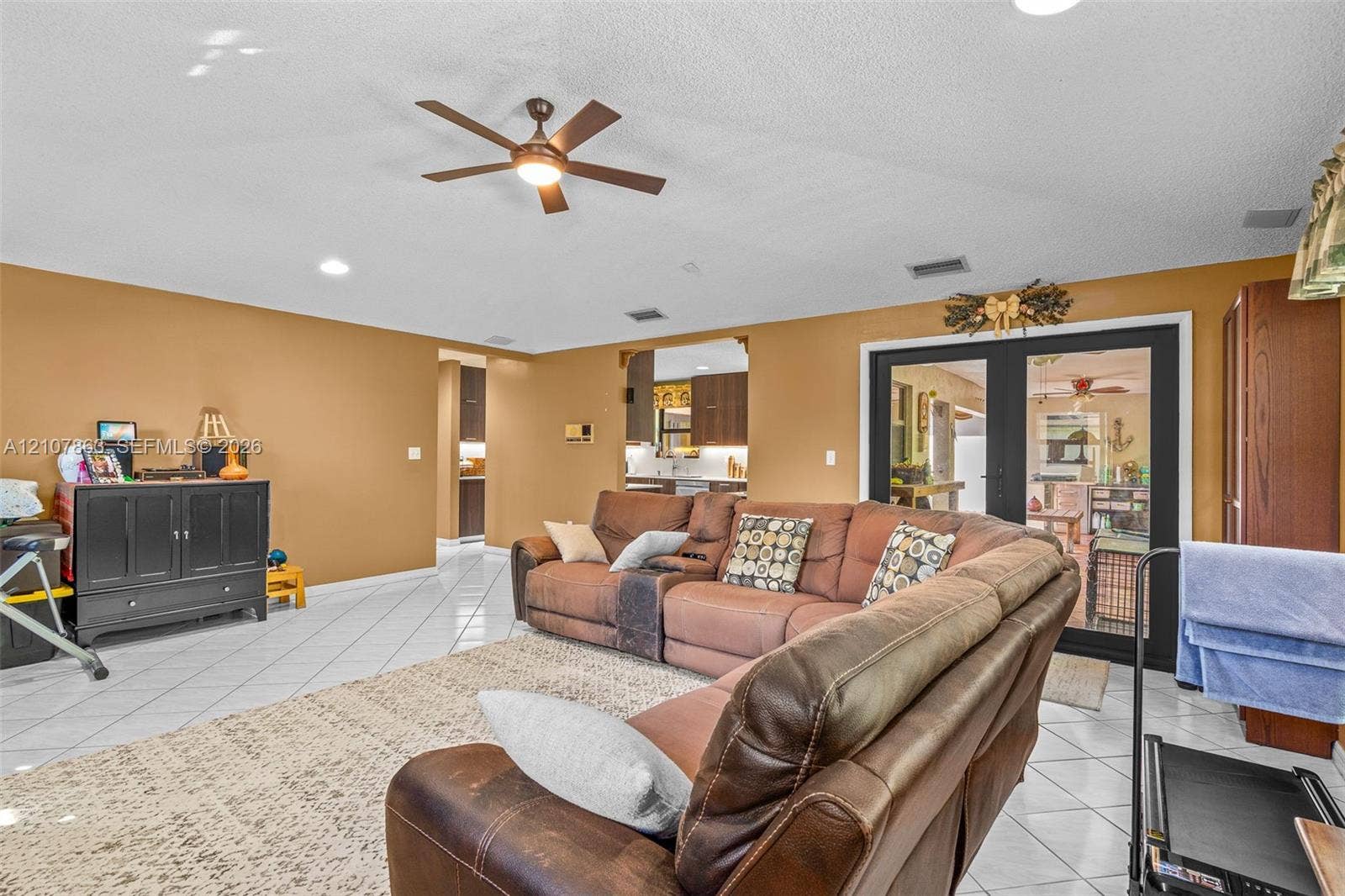 Living area featuring tile flooring, recessed lighting, a ceiling fan, and black-framed French doors