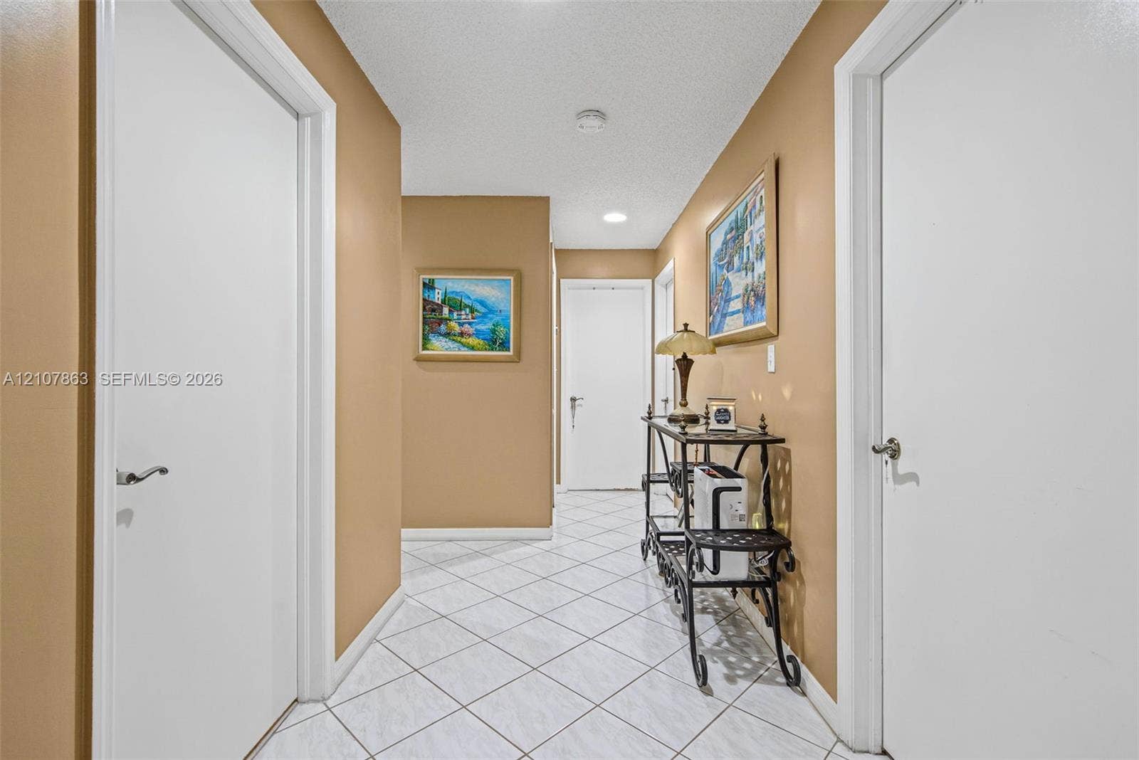 Hallway featuring white panel doors with lever-style hardware, recessed ceiling lighting, and diagonal-pattern tile flooring